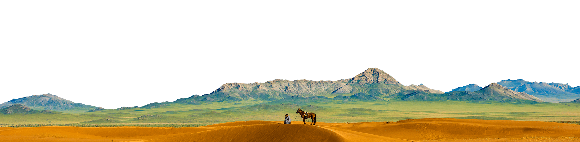 A person stands next to a horse on sandy dunes with a range of rocky mountains in the background under a green sky, painting an alluring travel destination for tourism enthusiasts.