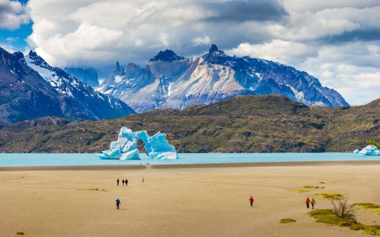 Tourists are walking on the shore of Lago Grey.
