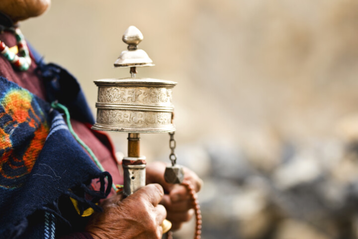 A person holds a traditional Tibetan prayer wheel adorned with intricate designs, reminiscent of Nepalese artistry.