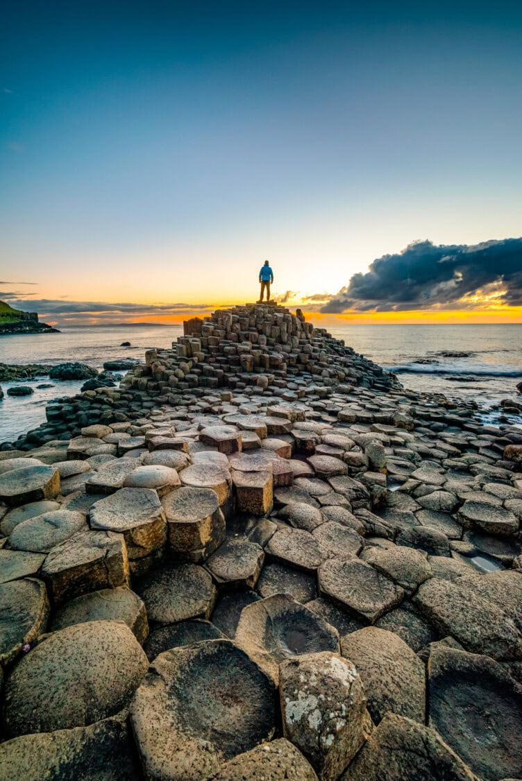 Standing on the basalt columns at Giant's Causeway during sunset, with the ocean shimmering under a cloudy sky, one can truly appreciate why this is one of Ireland's must-visit wonders.