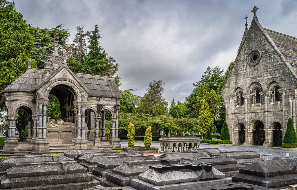 Nestled in the heart of Dublin, this old stone chapel and ornate mausoleum offer a picturesque glimpse into history, surrounded by whispering trees and timeworn gravestones under a cloudy sky—a must-see on any travel guide of things to do.