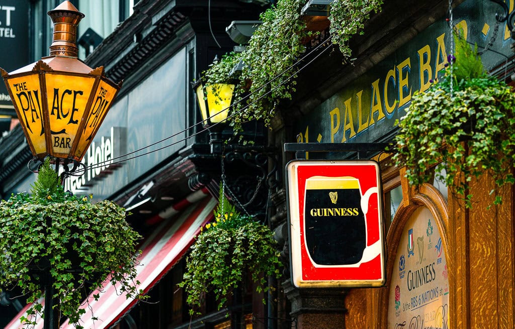 Street view of The Palace Bar in Dublin, adorned with hanging greenery and a prominent Guinness sign—an essential stop for travelers exploring the city's vibrant things to do.