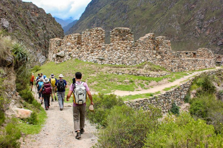 A group of hikers embarks on a thrilling 5-day adventure, trekking the renowned Inca Trail toward ancient stone ruins nestled among lush green mountains.