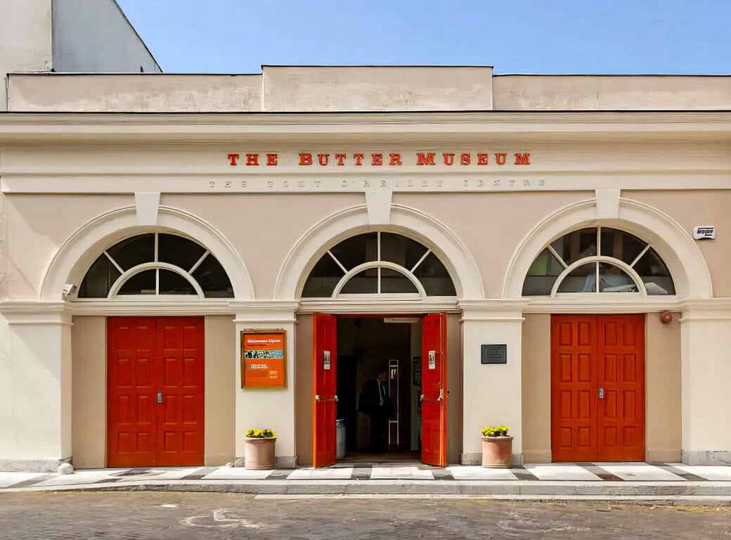 A cream-colored building with three arched windows and bright orange double doors displays a sign reading “The Butter Museum,” making it one of the must-see Cork attractions for anyone exploring things to do in Cork.